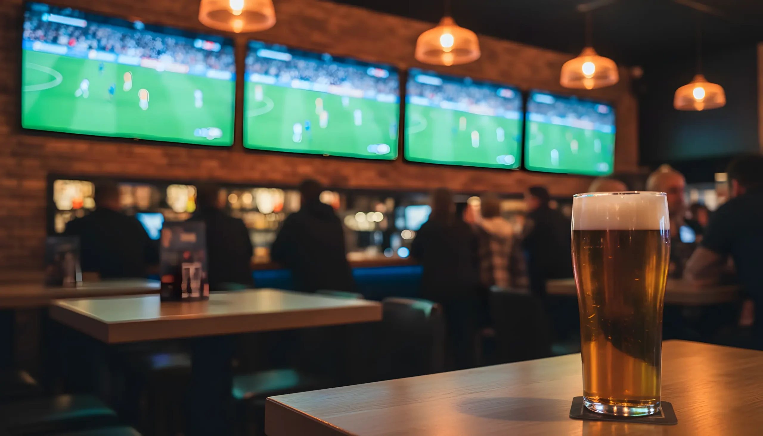 Ambiente de bar desportivo com ecrãs a mostrar jogo de futebol ao vivo