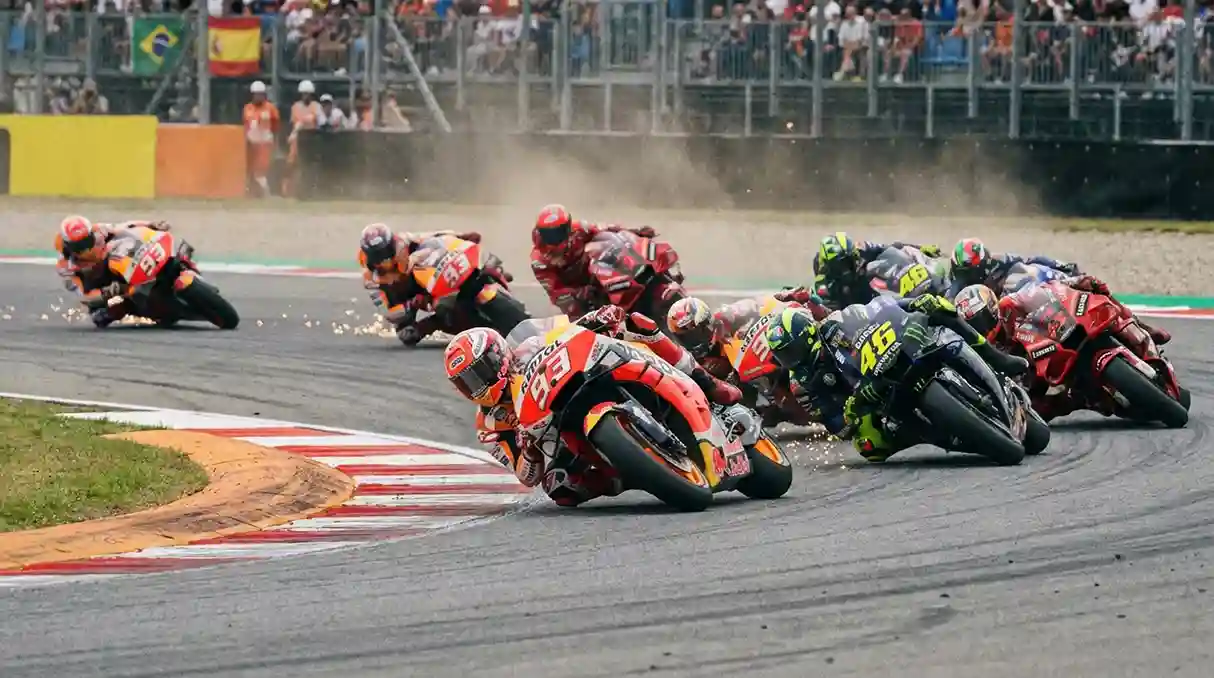Pilotos de MotoGP inclinados numa curva durante corrida